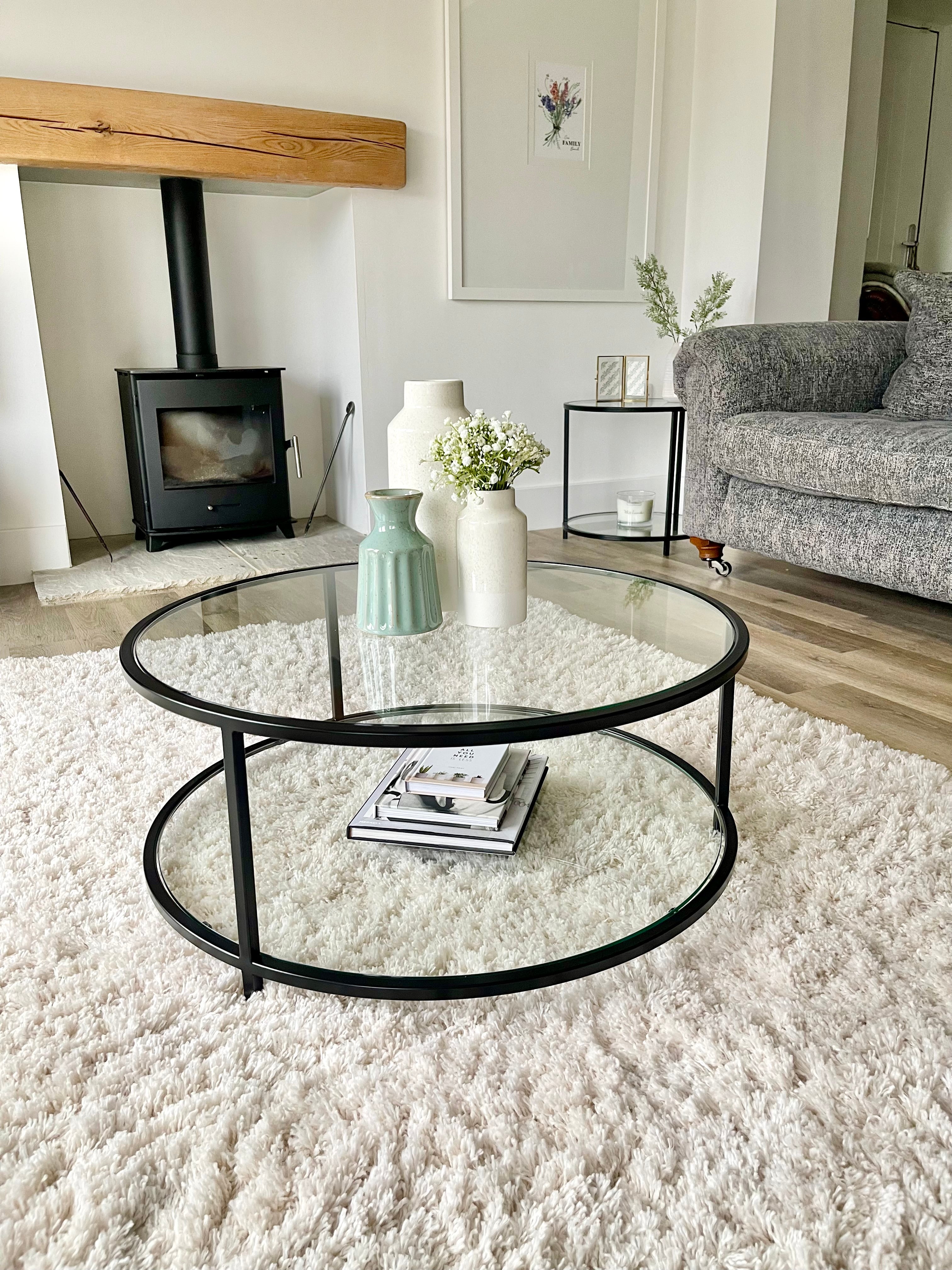 modern circular glass and metal coffee table styled with vases and books