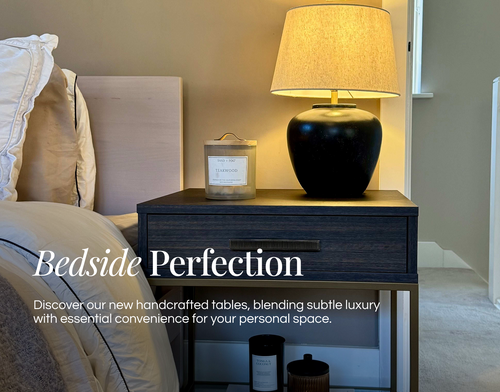 Handcrafted bedside table with lamp and candles in a bedroom setting.