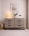 Wooden dresser with decorative items in a room with a lamp and plant.